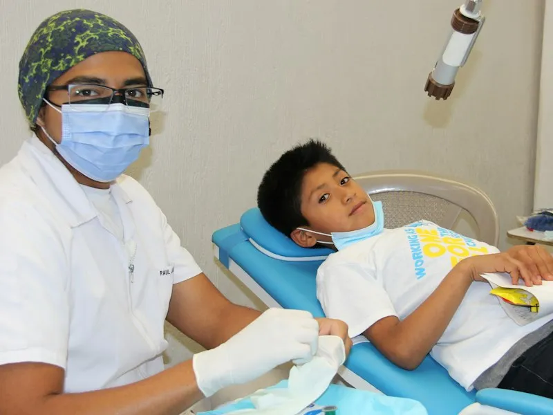 Odontóloga atendiendo con paciencia a un niño en el consultorio dental